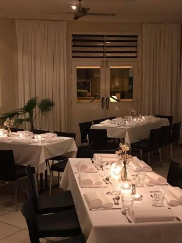 uma sala de jantar com mesas brancas e cadeiras pretas em The Playhouse Hotel em Barraba