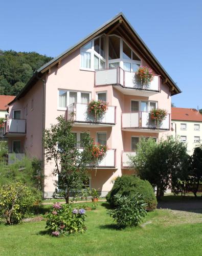 een roze gebouw met bloembakken op de balkons bij Hotel-Garni Elbgarten Bad Schandau in Bad Schandau