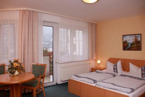 een slaapkamer met een bed, een tafel en een raam bij Hotel-Garni Elbgarten Bad Schandau in Bad Schandau