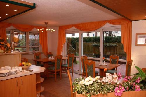 uma sala de jantar com mesa, cadeiras e janelas em Hotel-Garni Elbgarten Bad Schandau em Bad Schandau