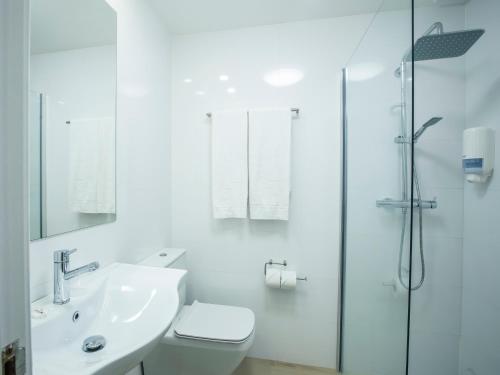 een witte badkamer met een wastafel en een douche bij Hotel Burlada in Burlada