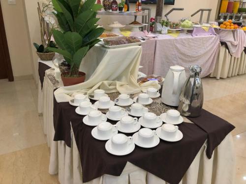 a table with white cups and saucers on it at Addissinia Hotel in Addis Ababa
