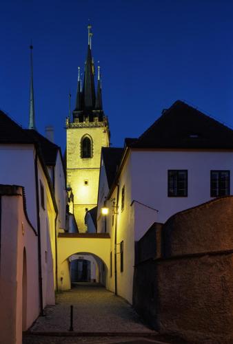 an alley with a building with a clock tower at night at Hotel Merlot in Louny