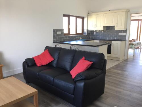 a living room with a black couch with two red pillows at Seafield House in Quilty