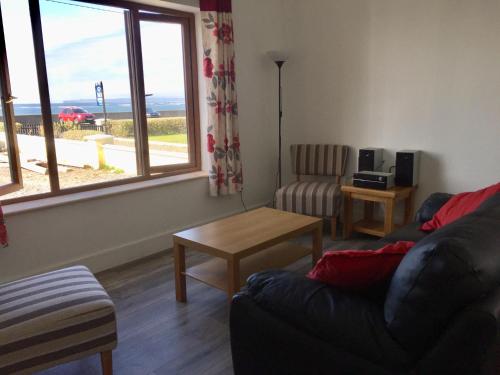 a living room with a couch and a table and a window at Seafield House at the beach in Quilty