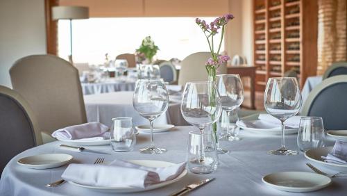 a table with glasses and plates and a vase with flowers at Fairplay Golf & Spa Resort in Benalup Casas Viejas