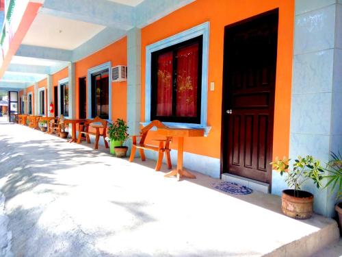 an orange building with a row of chairs and a door at Jun and Carol Beach Cottages in Pagudpud