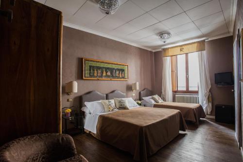 a hotel room with two beds and a chair at Hotel Residenza In Farnese in Rome