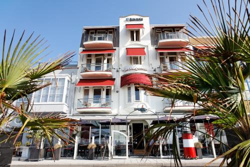 a white building with red balconies and palm trees at Hotel De Leugenaar in Vlissingen