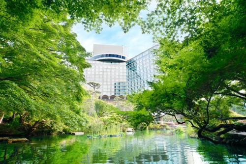 a river in a park with trees and a building at Hotel New Otani Tokyo The Main in Tokyo