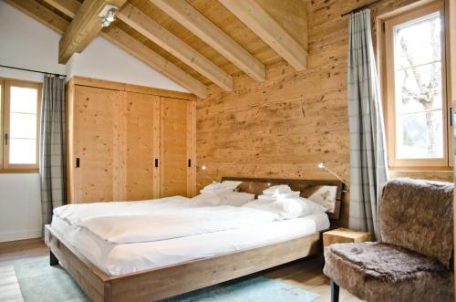 a bedroom with a large bed and a chair at Apartment Fortuna 5.5 - GriwaRent AG in Grindelwald