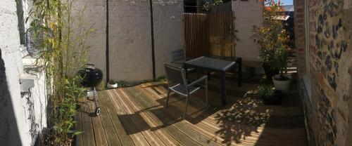 a patio with a table and chairs on a deck at Le HWell in Saint-Valery-sur-Somme
