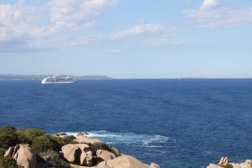 a boat in the ocean with rocks in the foreground at Capo Testa Tower in Capo Testa