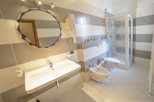 a bathroom with a sink and a toilet and a mirror at Hotel Sole in Chianciano Terme
