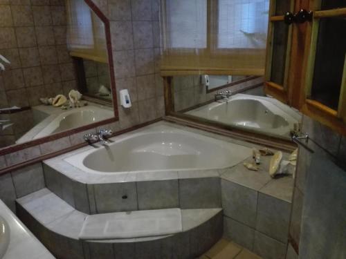 a large bath tub in a bathroom with a mirror at Vido Lodge and Conference Centre in Polokwane