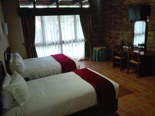 a hotel room with two beds and a window at Vido Lodge and Conference Centre in Polokwane