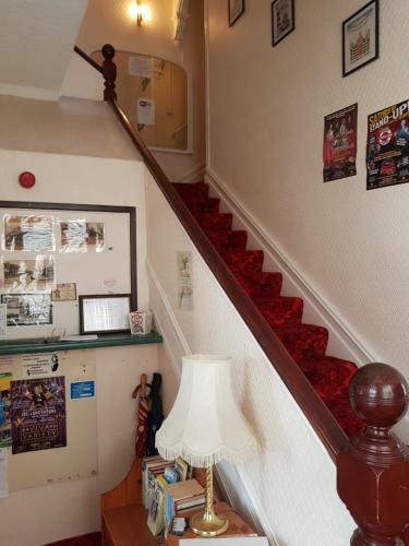 a stairway with a red carpet and a lamp at Cumbria Guest House in Lytham St Annes