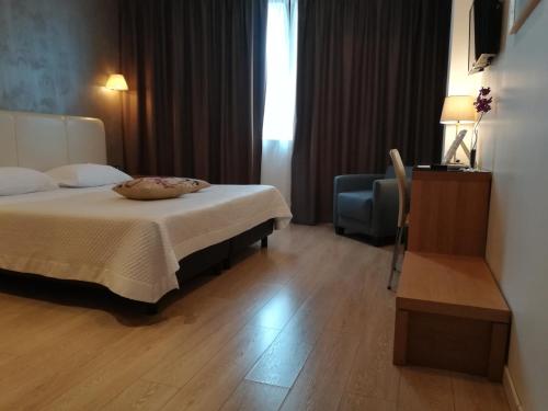 グラヴィーナ・イン・プーリアにあるRelais Peucetiaのベッドと椅子付きのホテルルーム