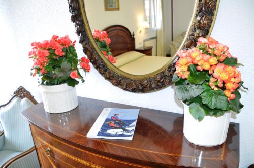 two vases with flowers on a table in front of a mirror at Hotel Museo Los Infantes in Santillana del Mar