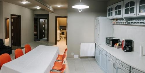 a kitchen with a white table and orange chairs at Meteor apartment XXL in Cluj-Napoca