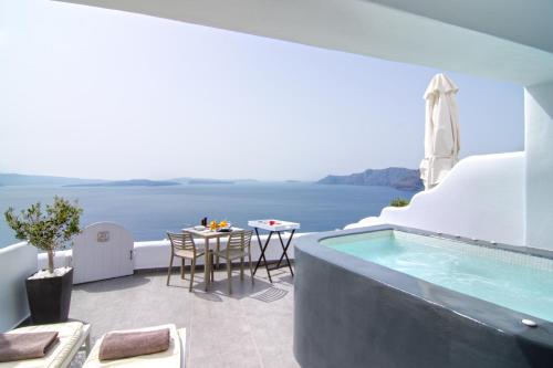 uma villa com uma piscina e uma mesa em Santorini Secret Suites & Spa, Small Luxury Hotels of the World em Oia