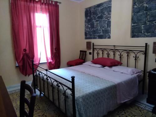 a bedroom with a bed and a window with red curtains at La Corte di Lucina in Terralba
