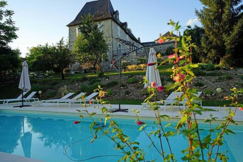 - une piscine avec des parasols et des chaises à côté d'un bâtiment dans l'établissement Chambre d'hôtes Au jardin de la Bachellerie, à La Bachellerie