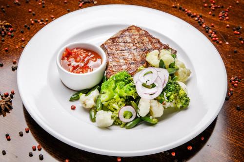 a plate of food with meat and vegetables on a table at Churchill-Inn in Vinnytsya
