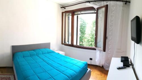 a bedroom with a blue bed and a window at Appartamento Sant'Elena in Venice