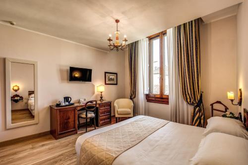 a hotel room with a bed and a desk and a mirror at Hotel Croce Di Malta in Florence