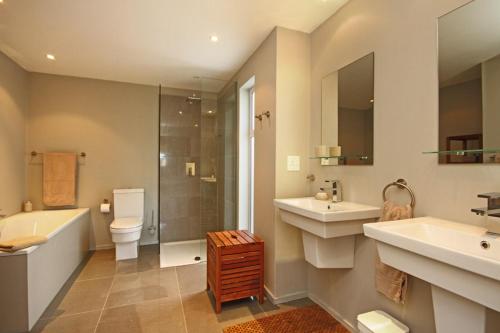 a bathroom with two sinks a toilet and a shower at Almondbury Cottage in Tokai