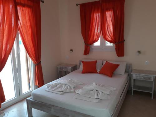 a bedroom with red curtains and a bed with red pillows at Eleni's Rooms in Antiparos Town