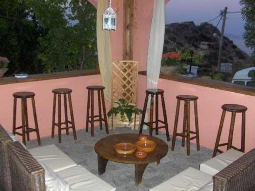 a patio with chairs and a table and bar stools at Cretan Village Hotel in Agios Nikolaos