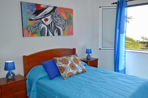 カマラ・デ・ロボスにあるApartment in Câmara de Lobosのベッドルーム1室(壁に絵画が描かれた青いベッド1台付)