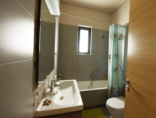 a bathroom with a sink and a toilet and a mirror at Panelma Villa Tranquil Coastal Retreat in Zacharo in Tholón