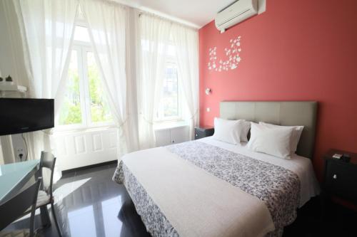 a bedroom with a bed and a red wall at Pinho Apartments, Studios and Rooms in Porto