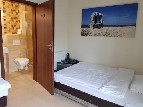 a bedroom with a bed and a bathroom with a toilet at Willa Cztery Brzozy Chałupy in Chałupy