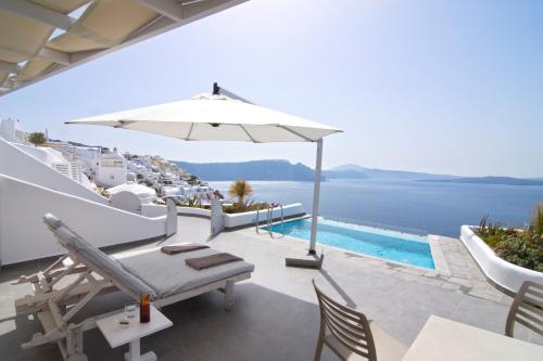 a patio area with chairs, tables and umbrellas at Santorini Secret Suites & Spa, Small Luxury Hotels of the World in Oia