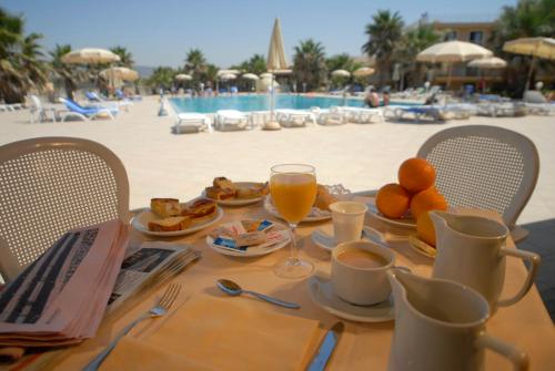 a table with a breakfast of oranges and orange juice on the beach at Dioscuri Bay Palace in San Leone