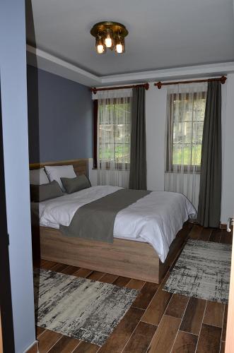 a bedroom with a large bed and two windows at Etap Uzungöl Suite Hotel in Uzungöl