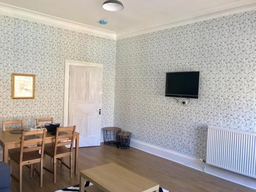 a living room with a table and a television on a wall at 233 Leith Apartment in Edinburgh