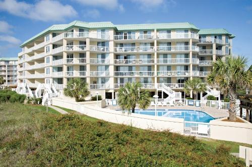 a large apartment building with a pool and palm trees at Litchfield Beach & Golf Resort in Pawleys Island