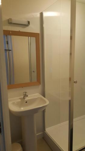 a bathroom with a sink and a shower with a mirror at Angel Guesthouse in Tiverton