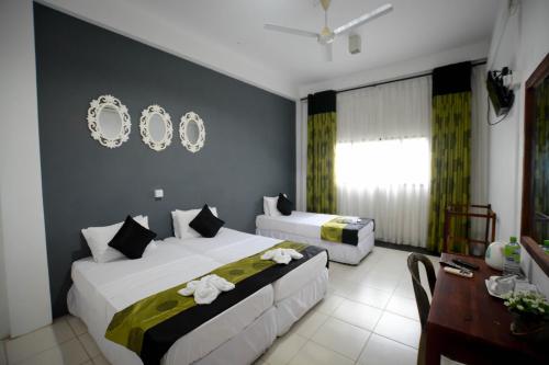 a hotel room with two beds and a desk at Pavana Resort in Embilipitiya