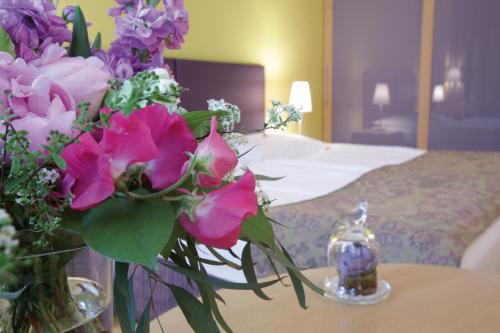 a vase of flowers on a table next to a bed at Appartement-Hotel an der Riemergasse in Vienna