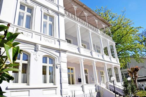 a white house with white columns at Appartementhaus Sellin in Ostseebad Sellin