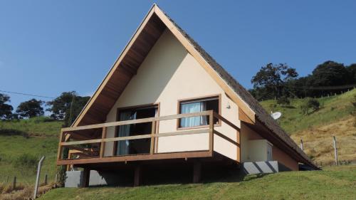 a house with a thatched roof on a hill at Chale Vale Encantado in São Bento do Sapucaí