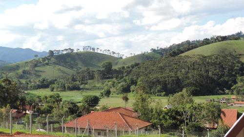 a view of green hills with trees and houses at Chale Vale Encantado in São Bento do Sapucaí