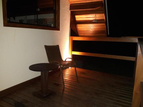 a room with a chair and a table and a television at Chale Vale Encantado in São Bento do Sapucaí