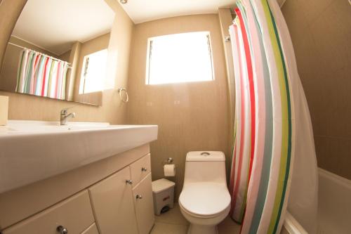a bathroom with a toilet and a sink and a window at TerraBahia Residences in Bahia Inglesa